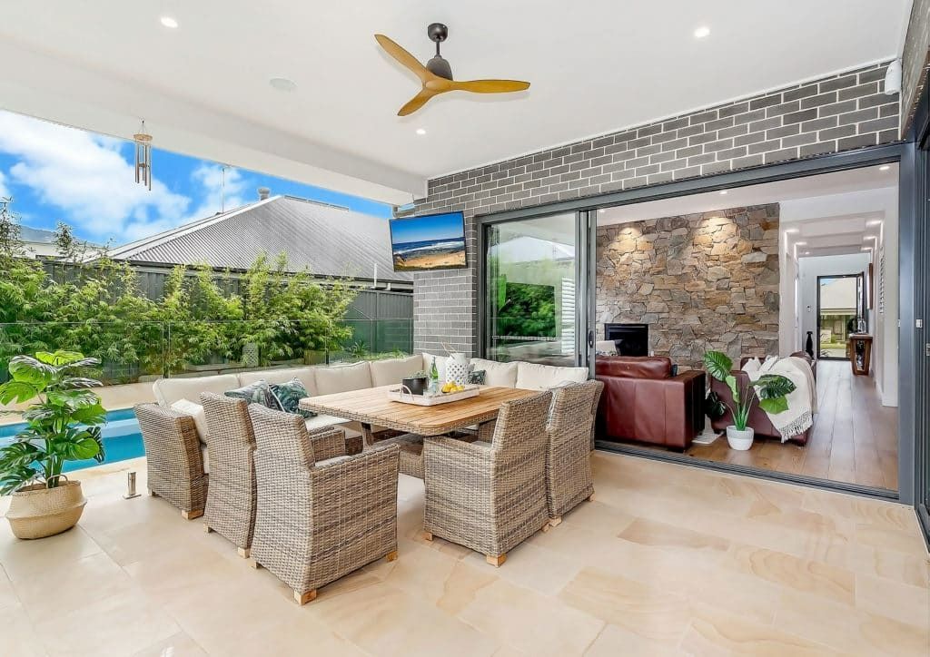 A Patio with A Table and Chairs and A Ceiling Fan — Evolution Building Group In Shellharbour, NSW