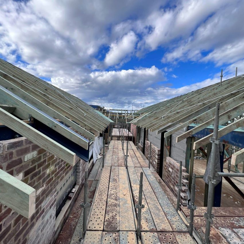 A Brick Building Under Construction with A Wooden Roof and Scaffolding — Evolution Building Group Dapto, NSW