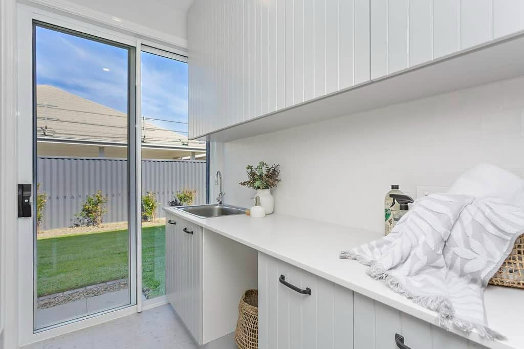A Laundry Room with White Cabinets, a Sink, and A Sliding Glass Door — Evolution Building Group Dapto, NSW