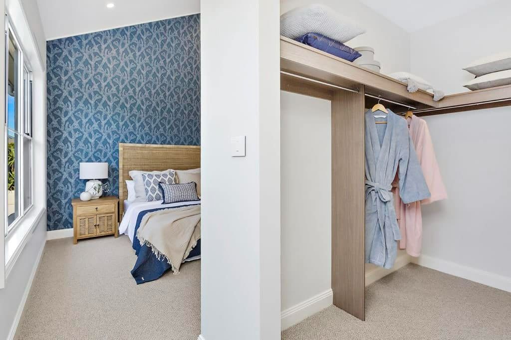 A Bedroom with A Bed and A Closet with Clothes Hanging on The Wall — Evolution Building Group Dapto, NSW
