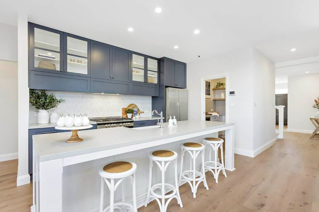 A Kitchen with A Long Island and Stools in A House — Evolution Building Group Dapto, NSW