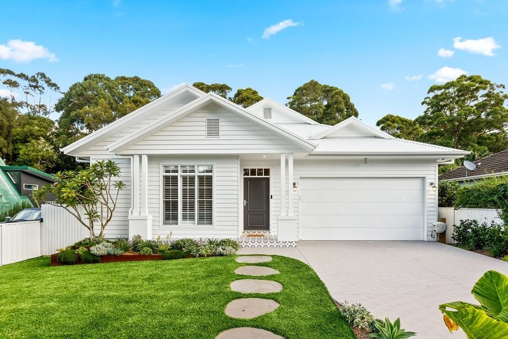 A White House with A White Garage Door Is Sitting on Top of A Lush Green Lawn — Evolution Building Group Dapto, NSW