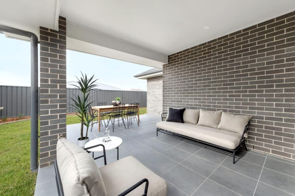 A Patio with A Couch, Chair, Table and Brick Wall — Evolution Building Group Dapto, NSW
