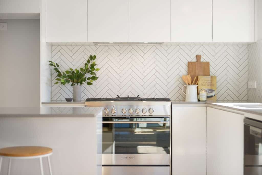 A Kitchen with White Cabinets, Stainless Steel Appliances, and A Stove — Evolution Building Group Dapto, NSW