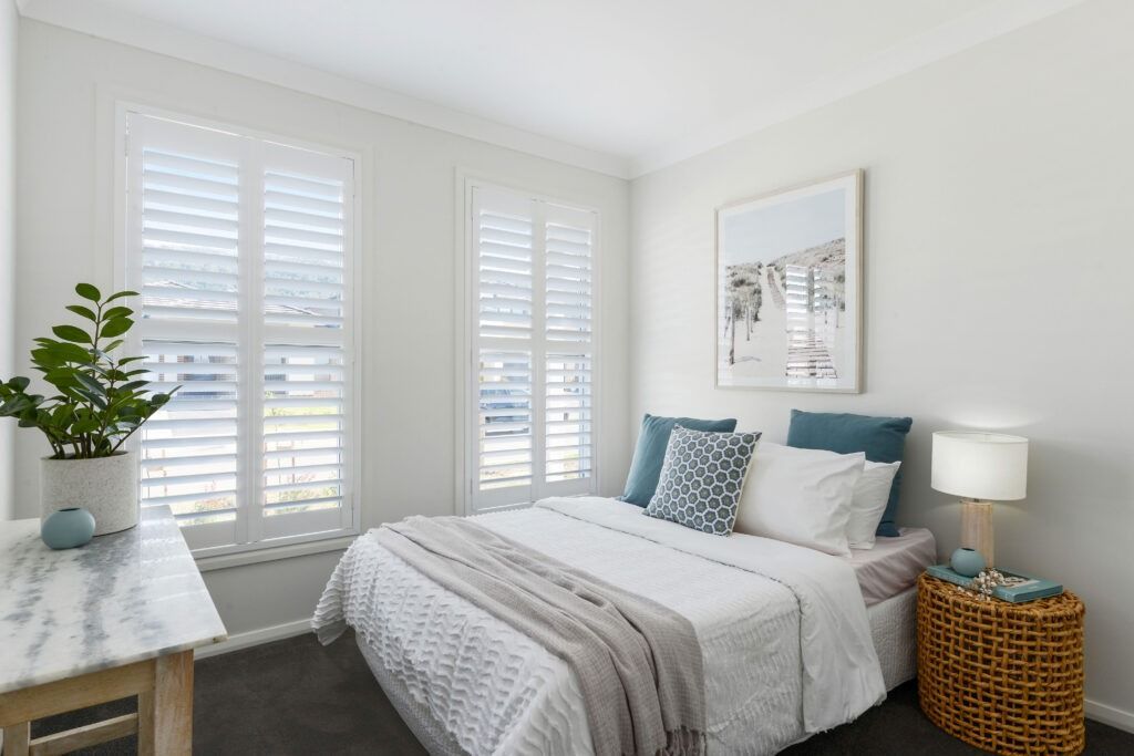 A Bedroom with A King Size Bed, Nightstand, Table and Shutters — Evolution Building Group Dapto, NSW