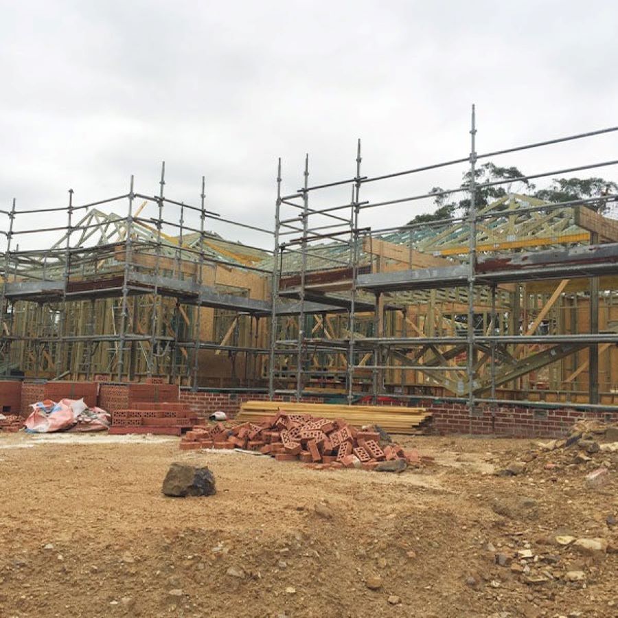 A Construction Site with Scaffolding and Bricks in The Dirt — Evolution Building Group Dapto, NSW