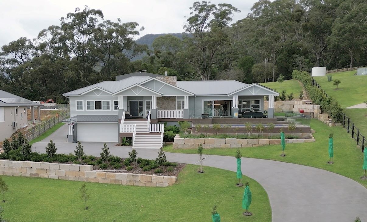 A Large House Is Sitting on Top of A Lush Green Hillside Surrounded by Trees — Evolution Building Group Dapto, NSW