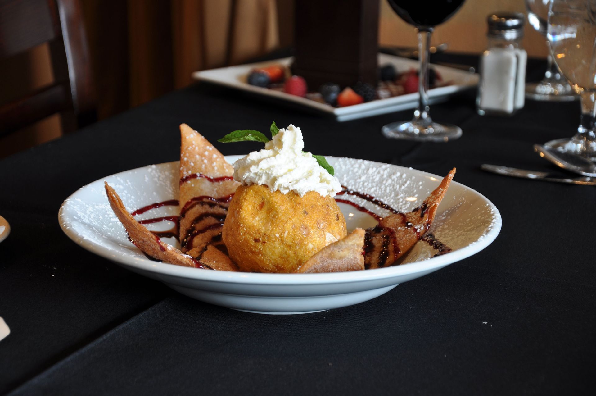 A plate of food on a table with a glass of wine in the background