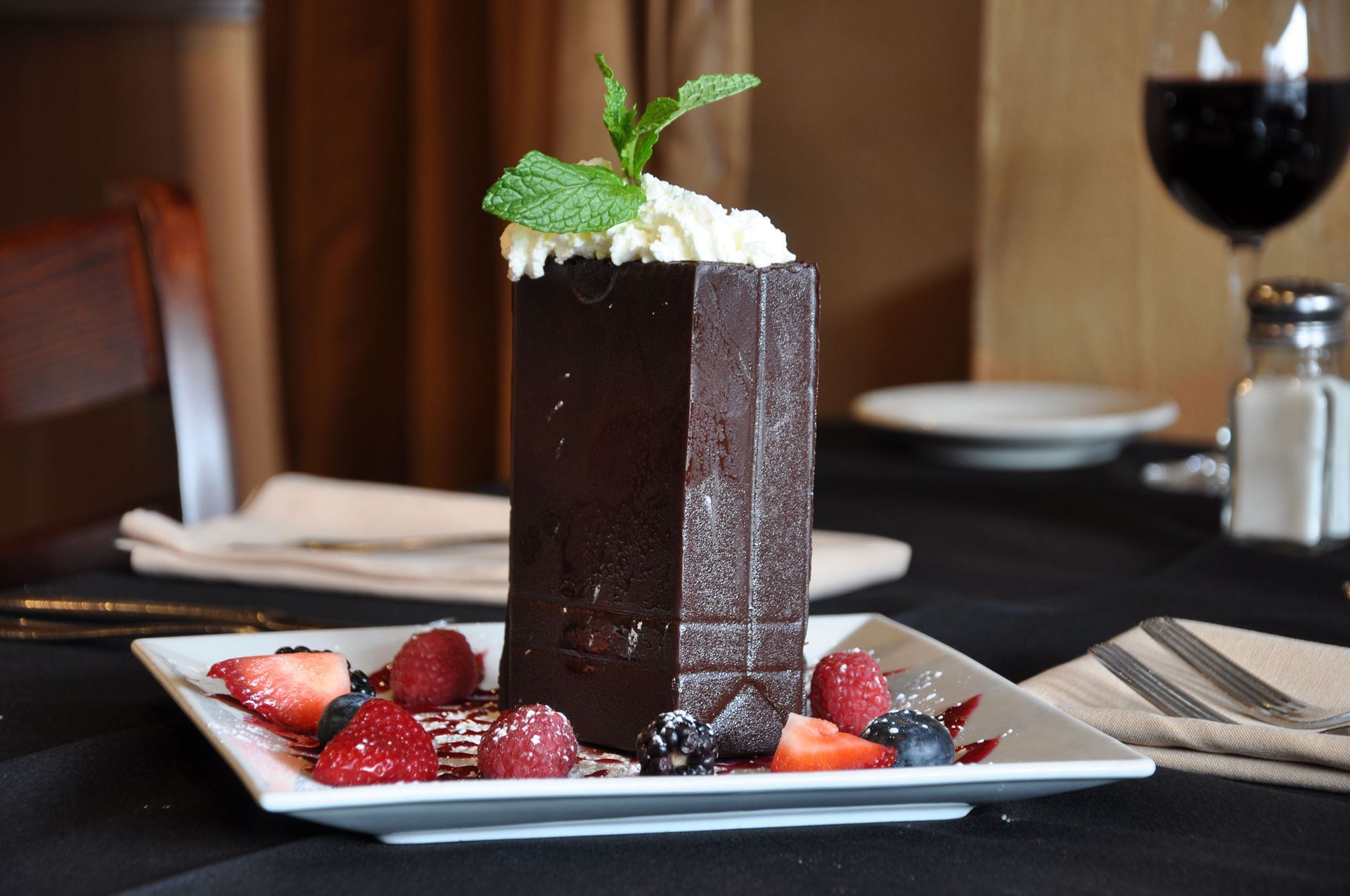 A chocolate dessert with whipped cream and berries on a plate