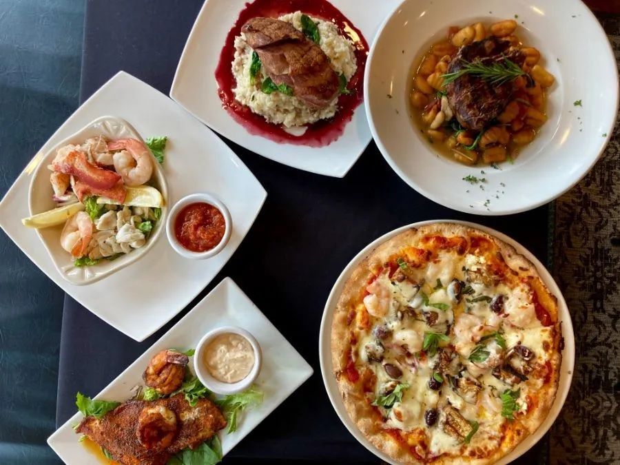 A table topped with plates of food including a pizza and a taco.