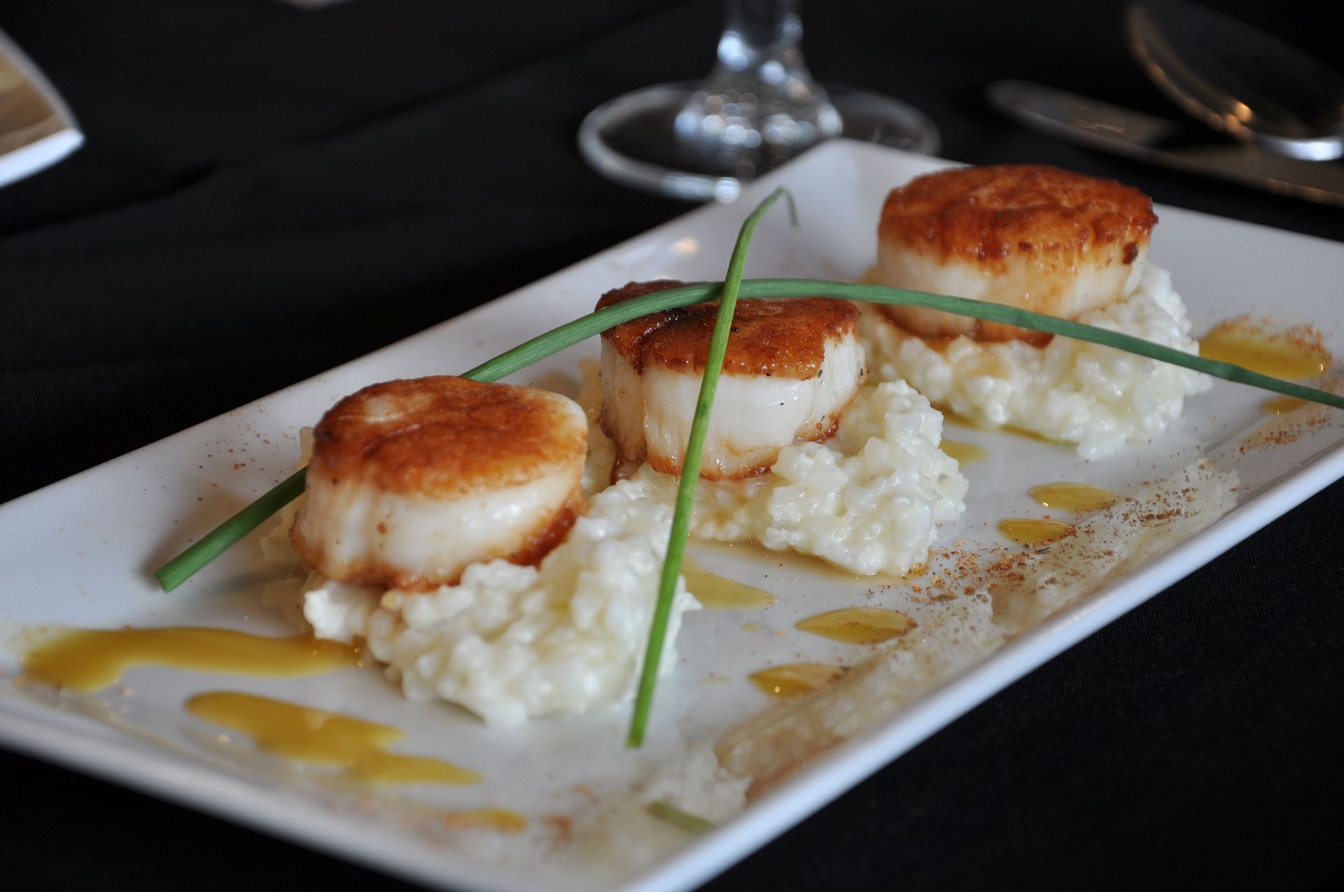 A white plate topped with scallops and mashed potatoes