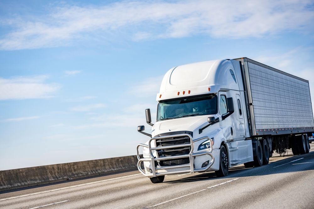 A white semi truck is driving down a highway.