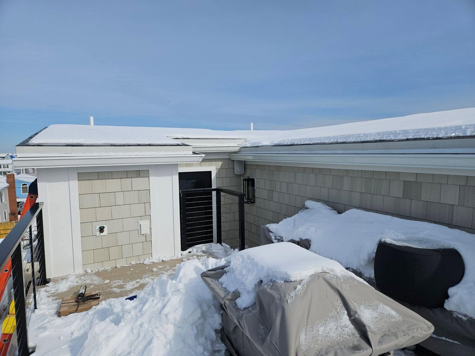 Snow-covered rooftop with HVAC units and a clear blue sky