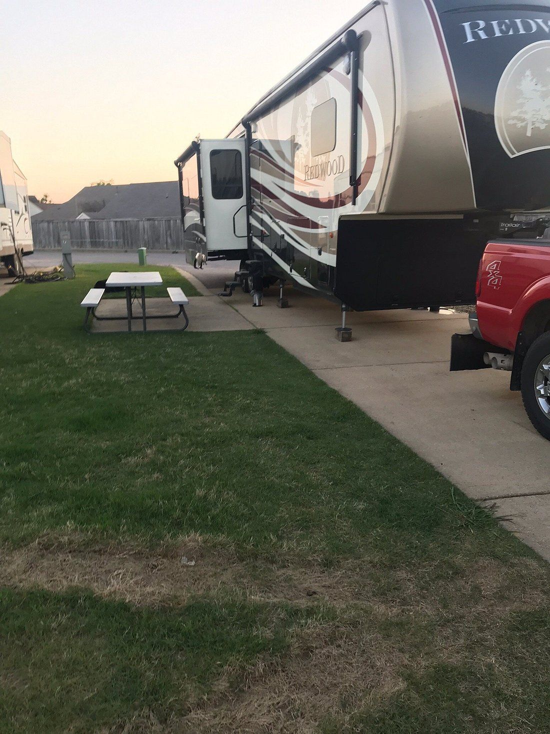 A rv is parked in a grassy area next to a picnic table.