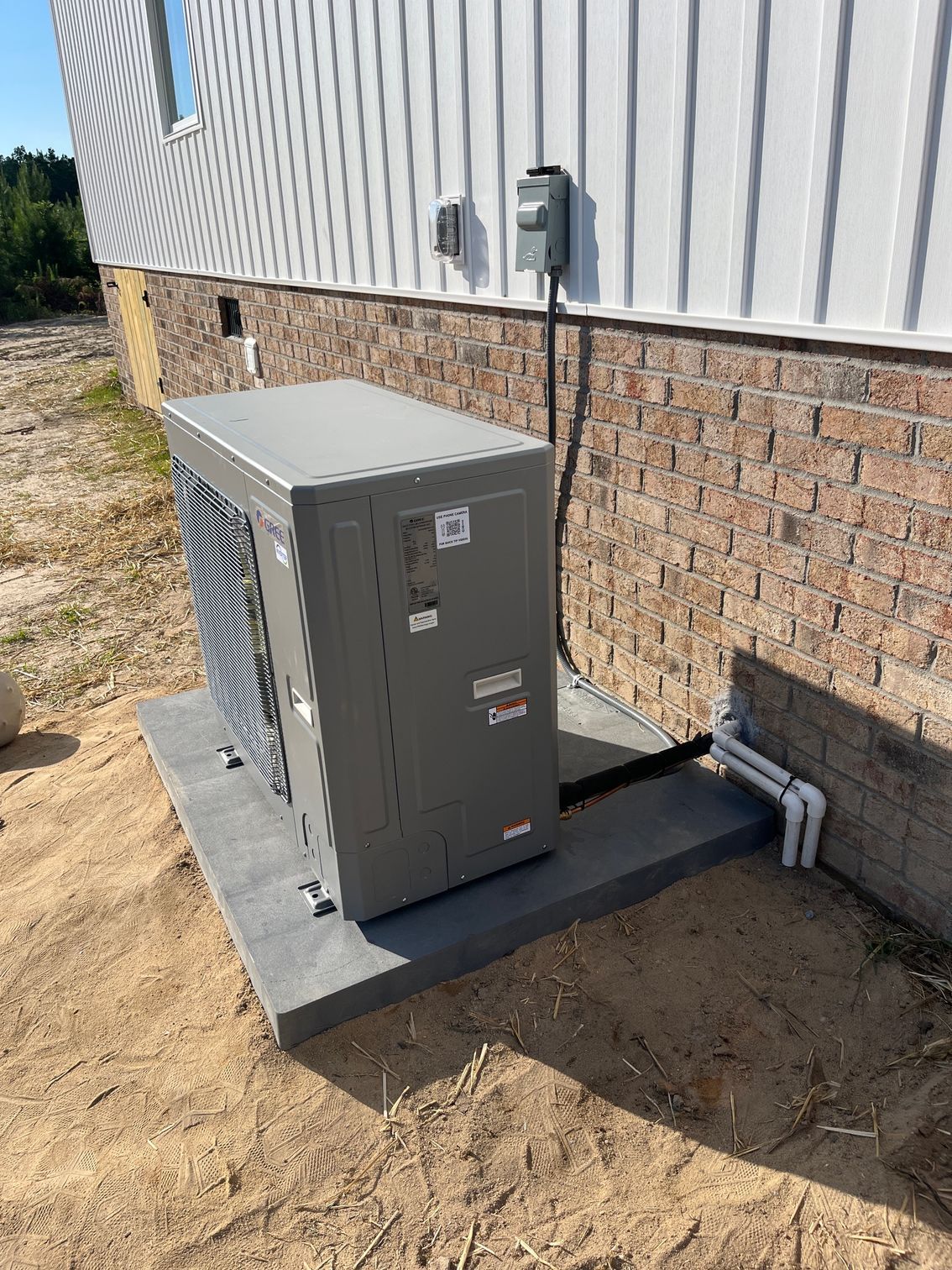 A large box is sitting on the side of a brick building.