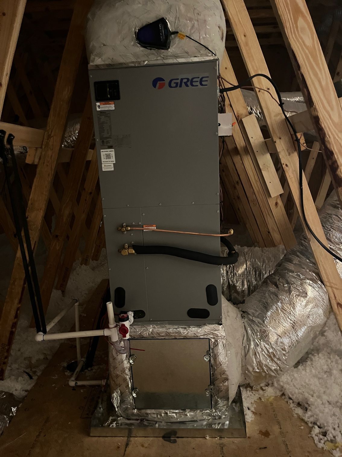 A gree air conditioner is sitting in the attic of a house.