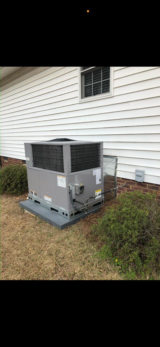 A large air conditioner is sitting on the side of a house.