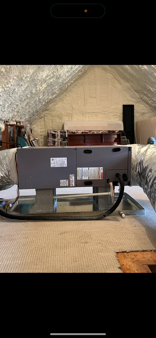 A picture of an air conditioner being installed in an attic.