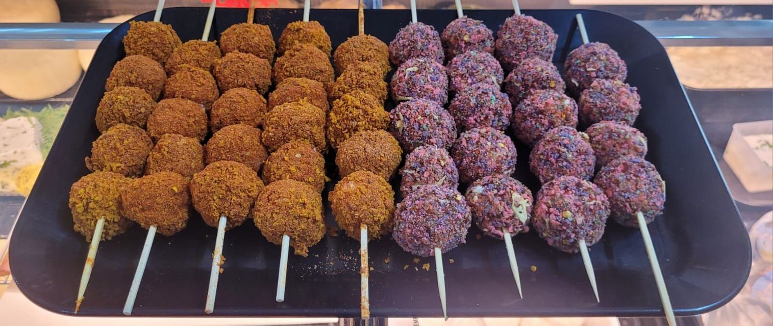 un vassoio nero pieno di polpette su spiedini.
