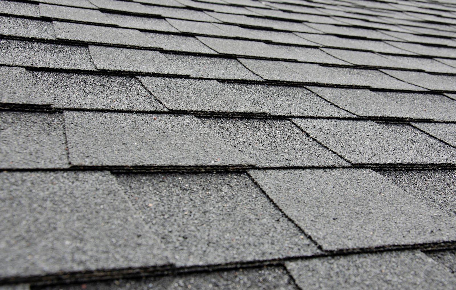 Close-up of gray asphalt roof shingles with layered rows and rough texture