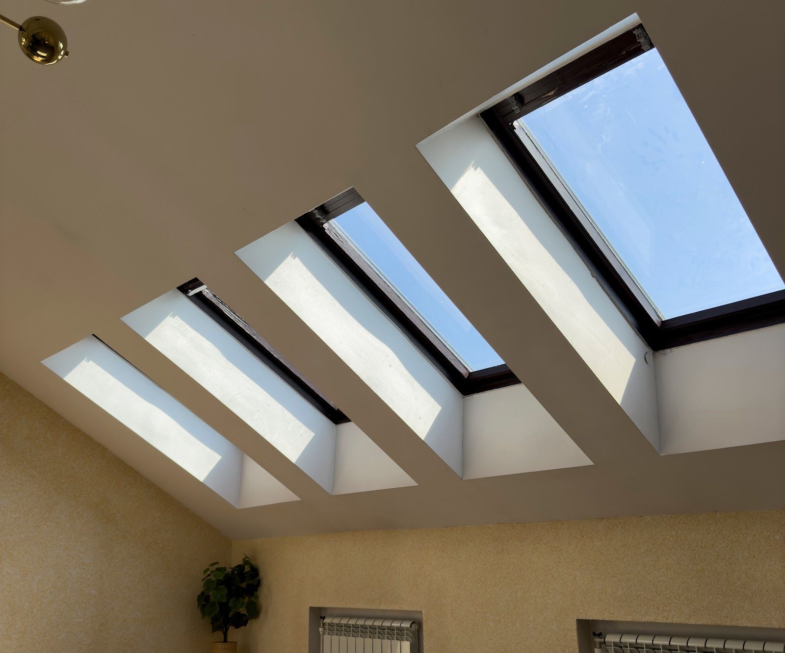 Skylight windows set into a slanted beige ceiling, with blue sky visible outside.