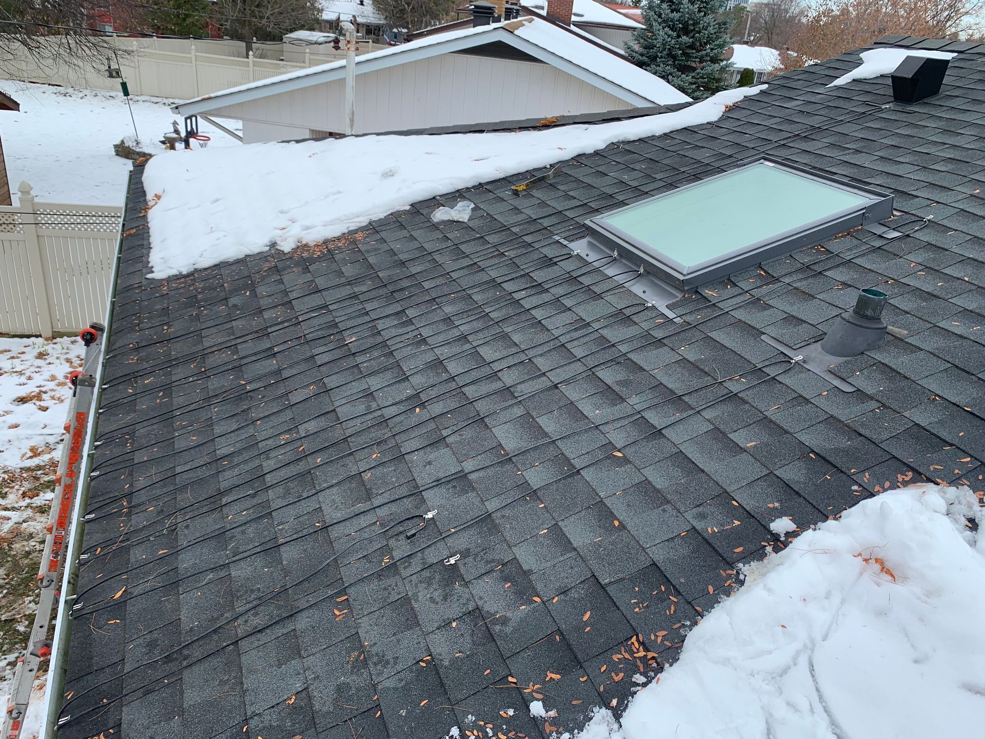 Snow-covered shingled roof with a skylight on a house in winter
