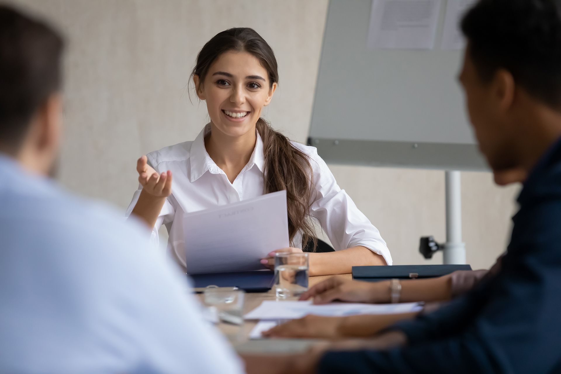 Business meeting with a smiling presenter holding papers at a conference table