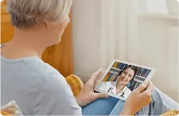 Elderly woman having a video call with a doctor on a tablet indoors.