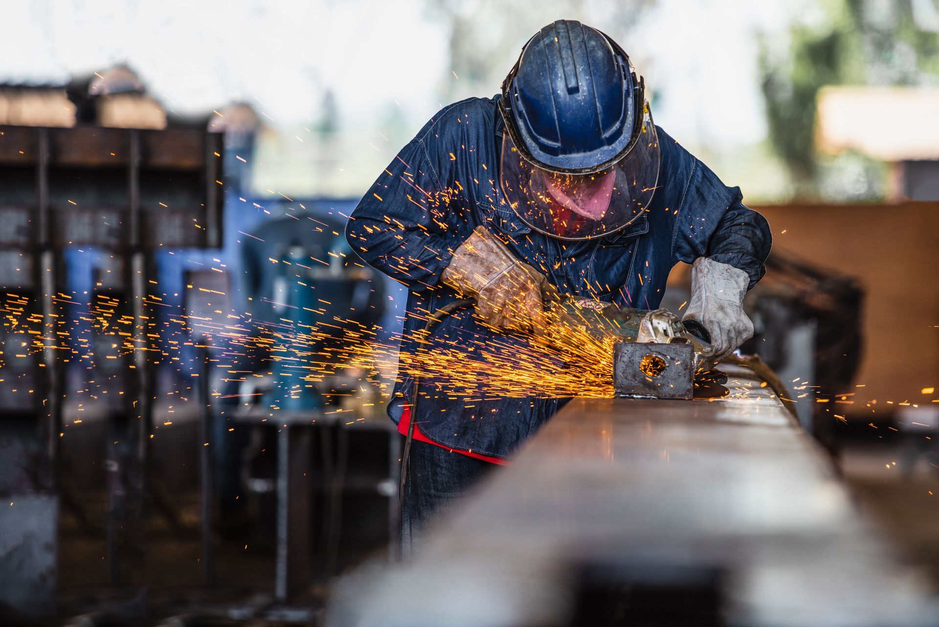 Worker using an angle grinder to cut metal, creating bright sparks
