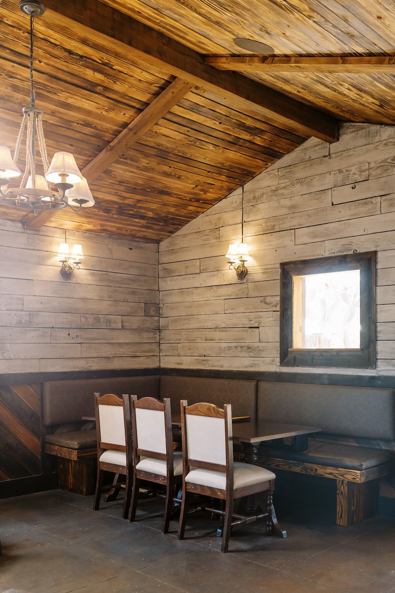 A dining room with tables and chairs and a wooden ceiling.