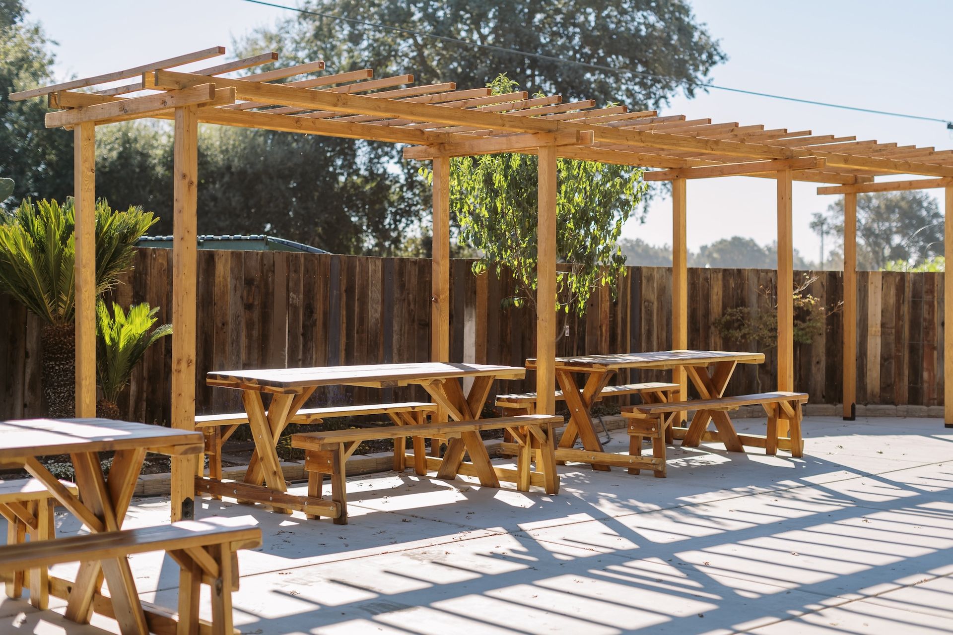 A row of wooden picnic tables under a wooden pergola