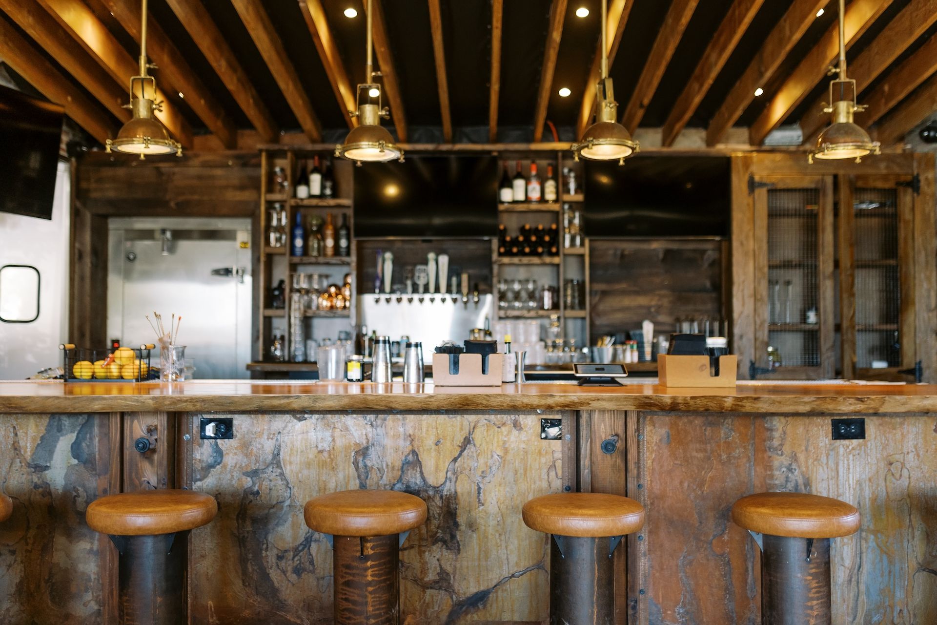 A restaurant with a long wooden bar and stools.