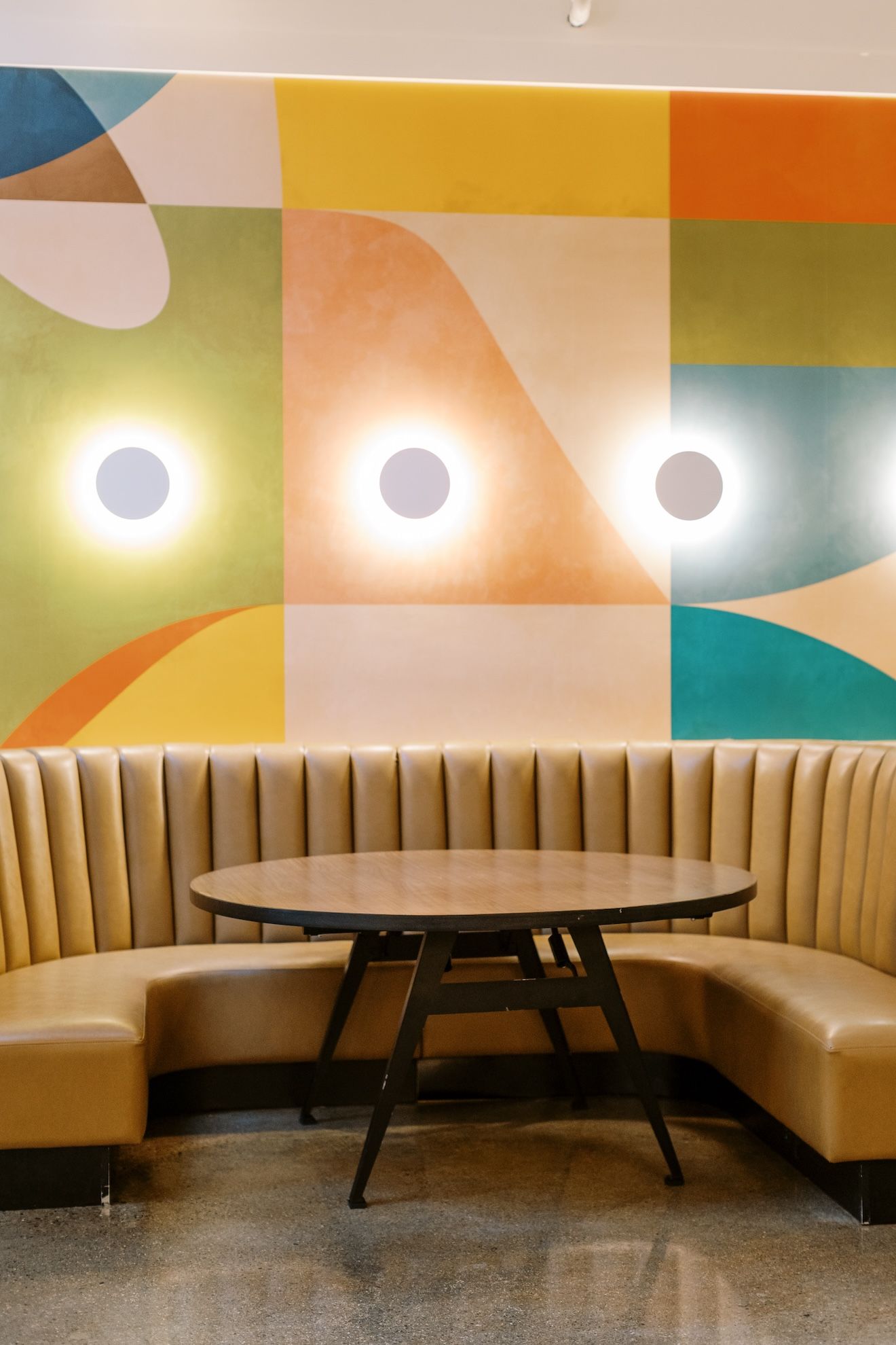 There is a table in the middle of the room with a colorful wall behind it.