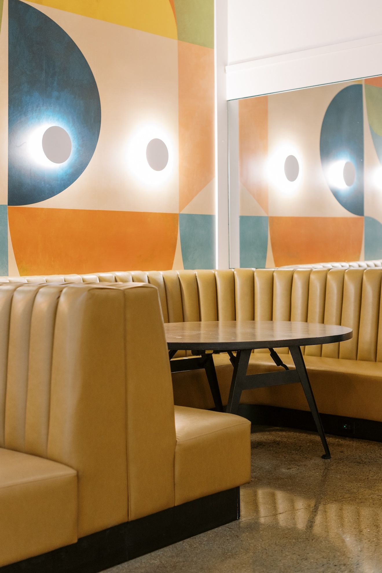 A restaurant booth with a table and a painting on the wall