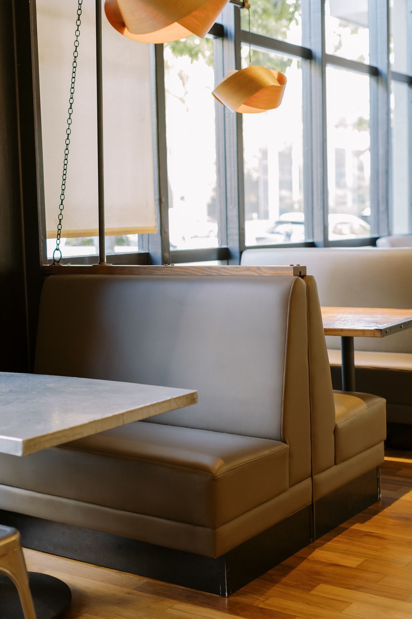 A restaurant booth with tables and chairs in front of a window.