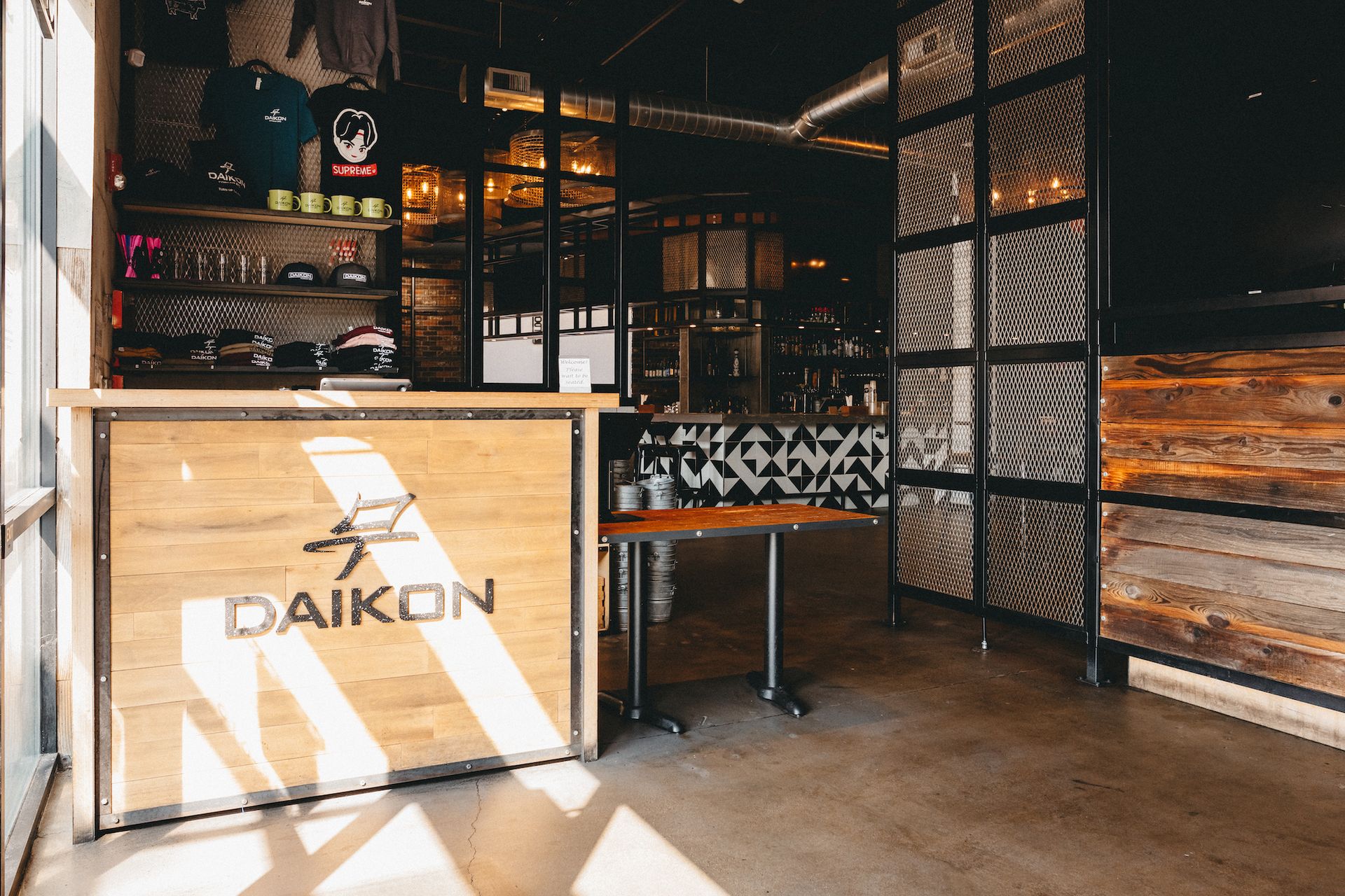 The inside of a restaurant with a wooden counter and tables.