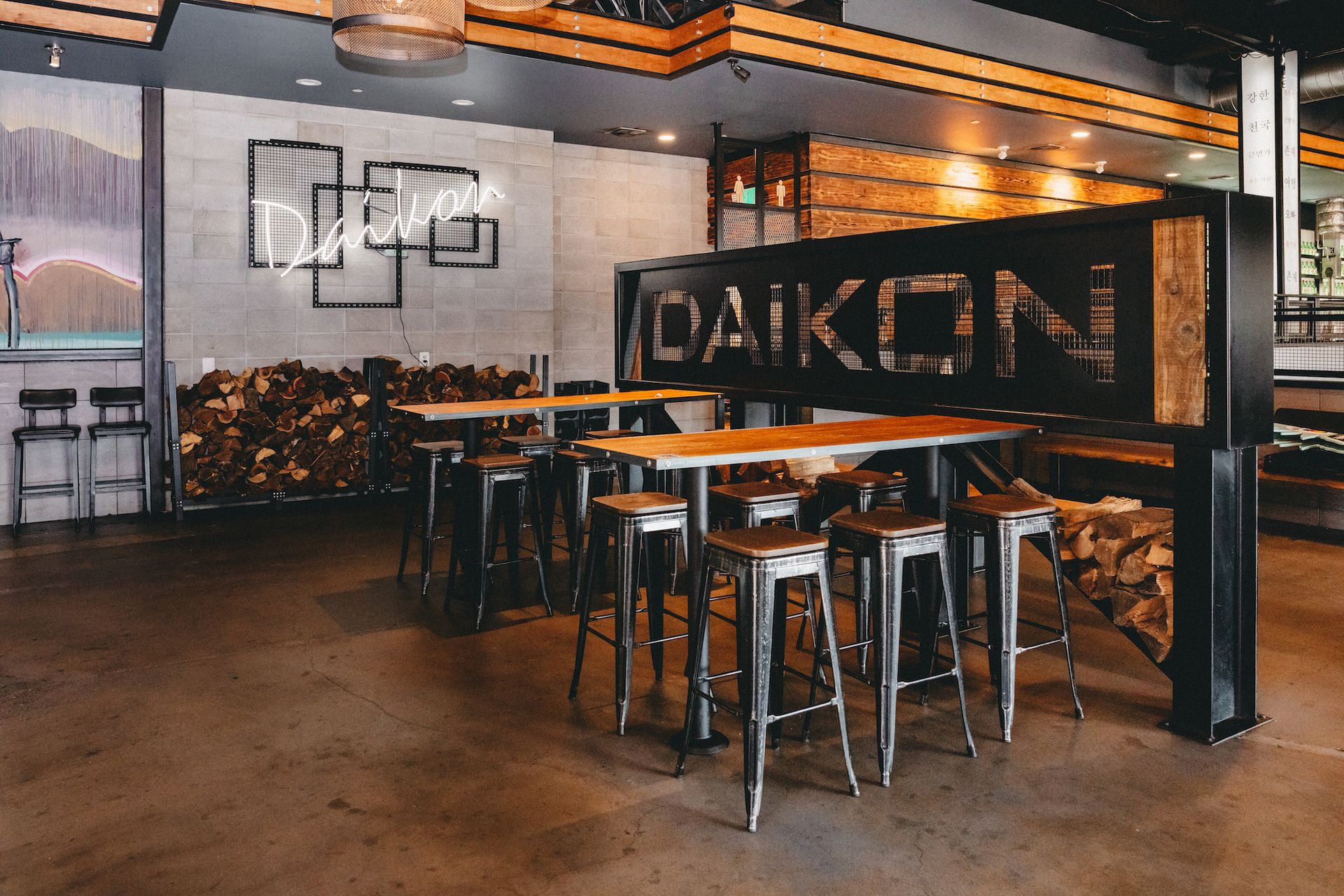 A restaurant with tables and stools and a sign that says daikon.
