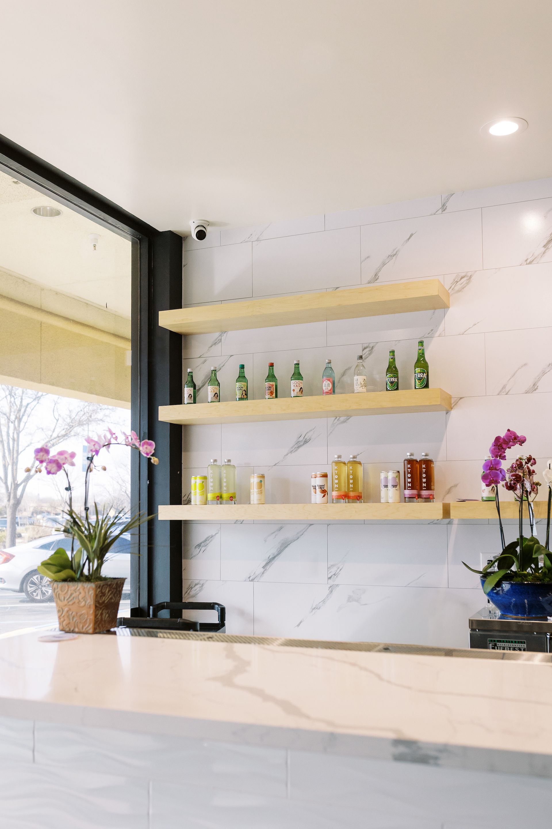 A restaurant with a counter, shelves, and a window.