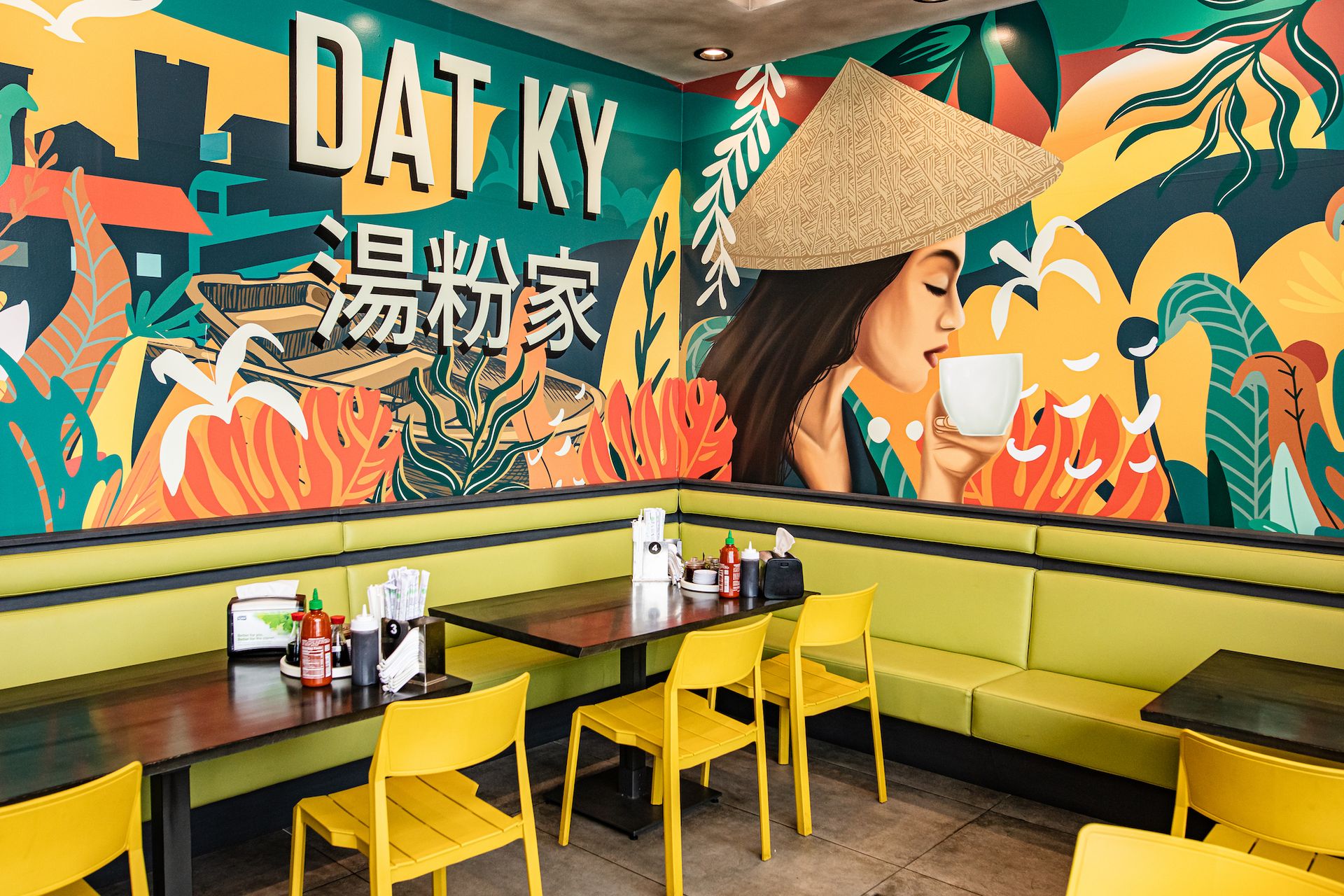 A restaurant with tables and chairs and a mural on the wall.