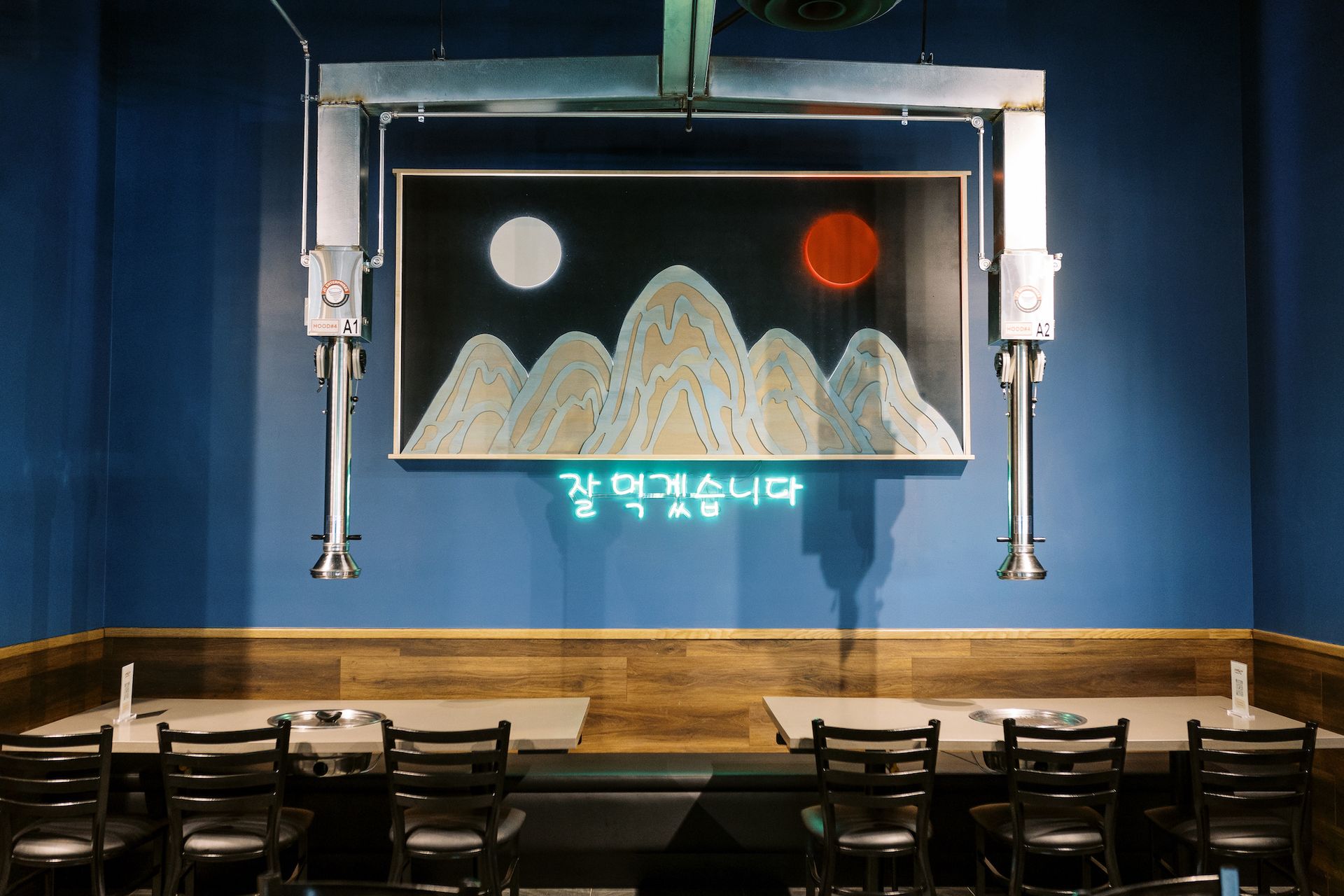 A restaurant with tables and chairs and a painting on the wall.