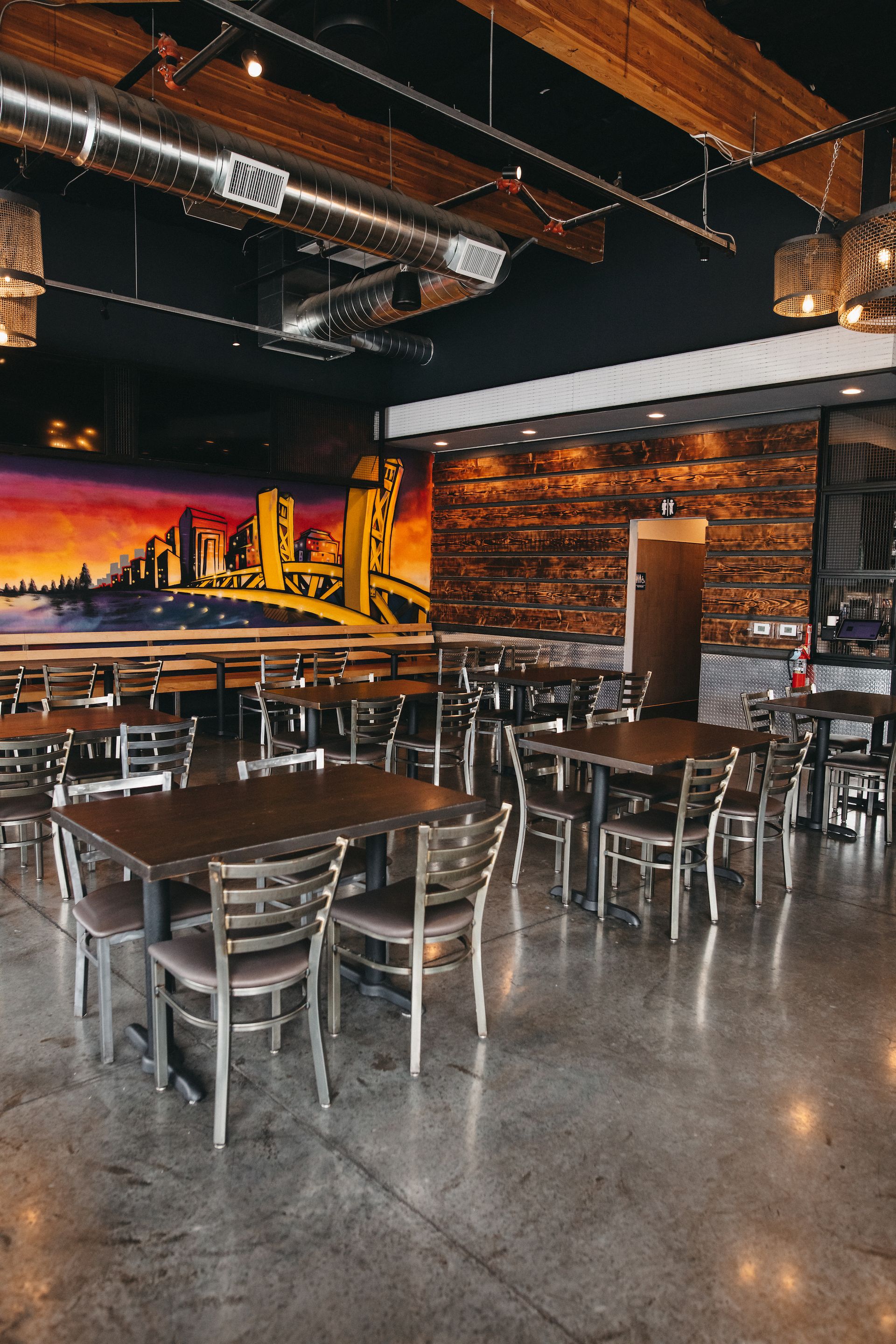 A restaurant with tables and chairs and a mural on the wall.