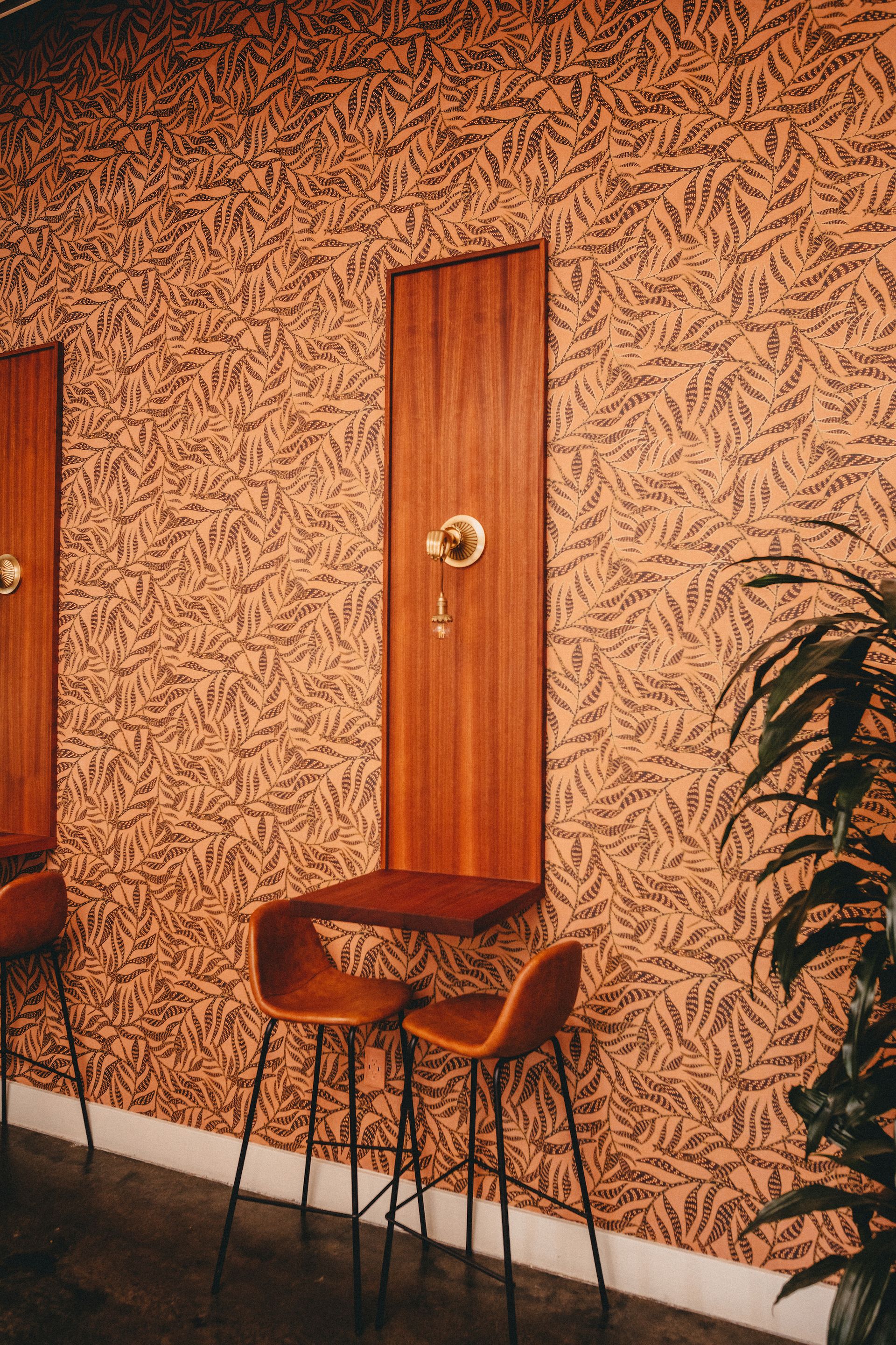 Two chairs and a table are sitting in front of a wall with a patterned wallpaper.