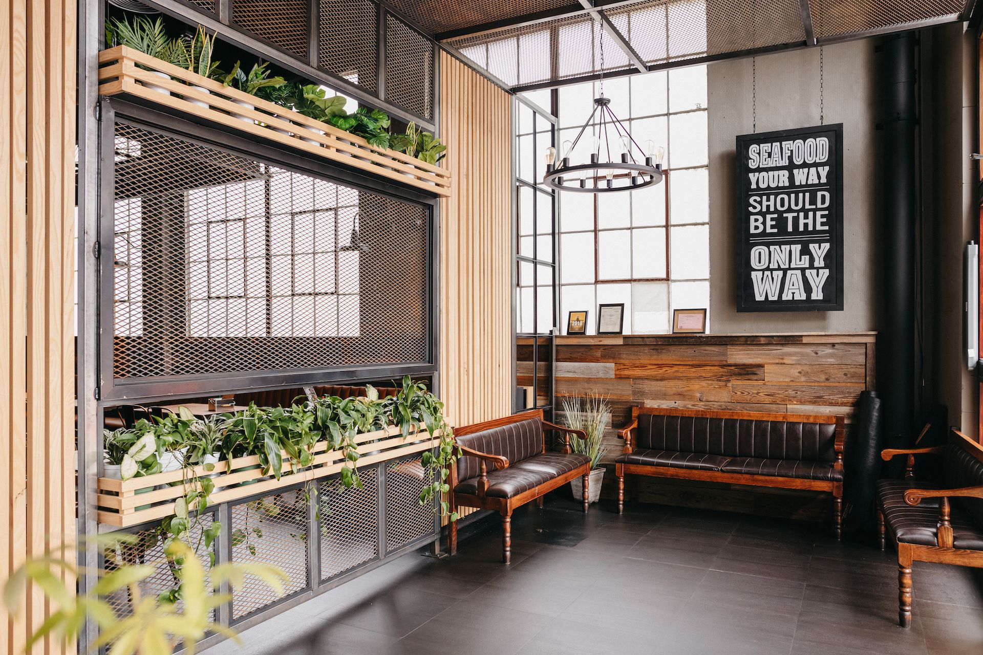 A restaurant with a bench, plants & wooden designs