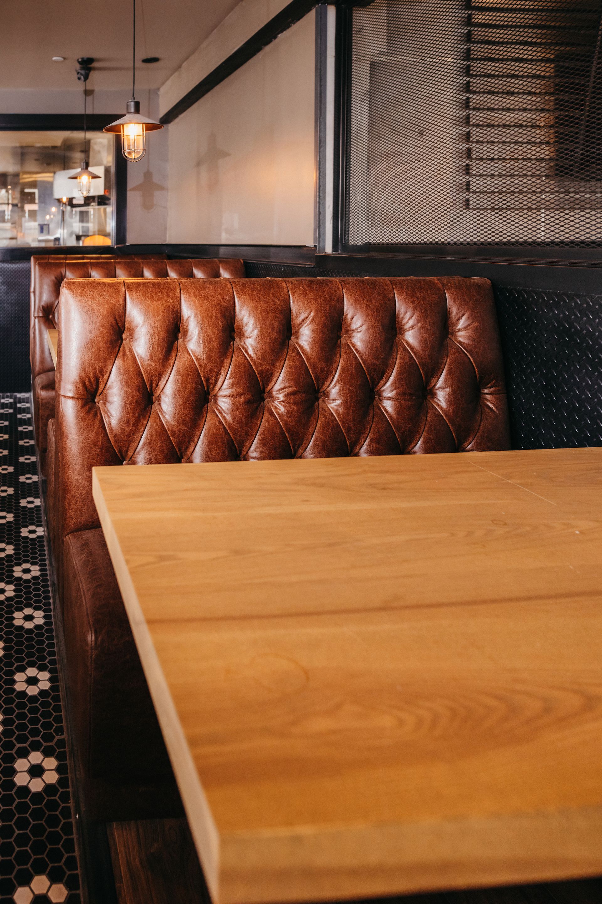 A restaurant booth with a brown leather seat and a wooden table.