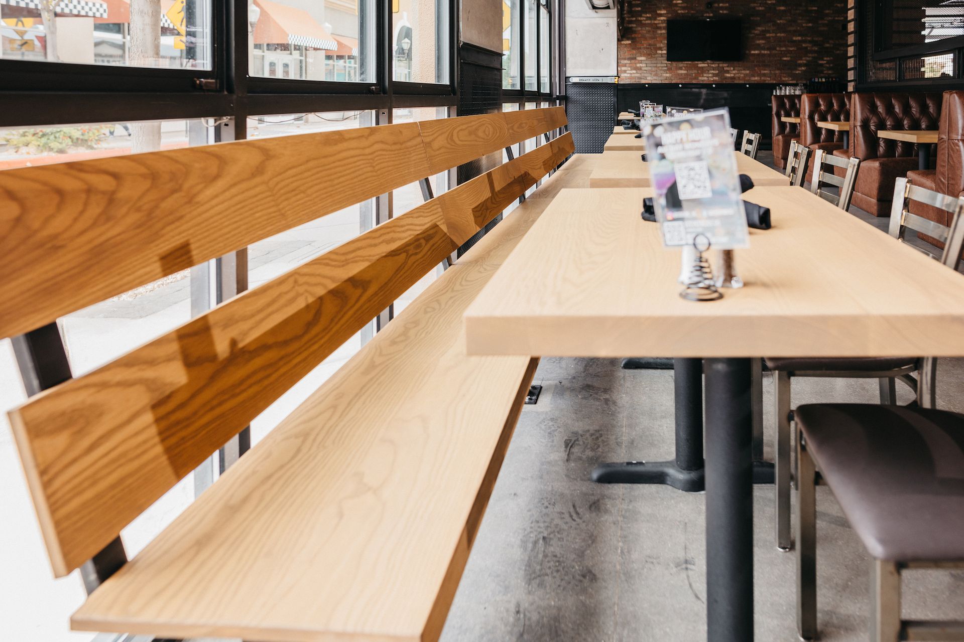 A restaurant with tables and benches with wooden backs
