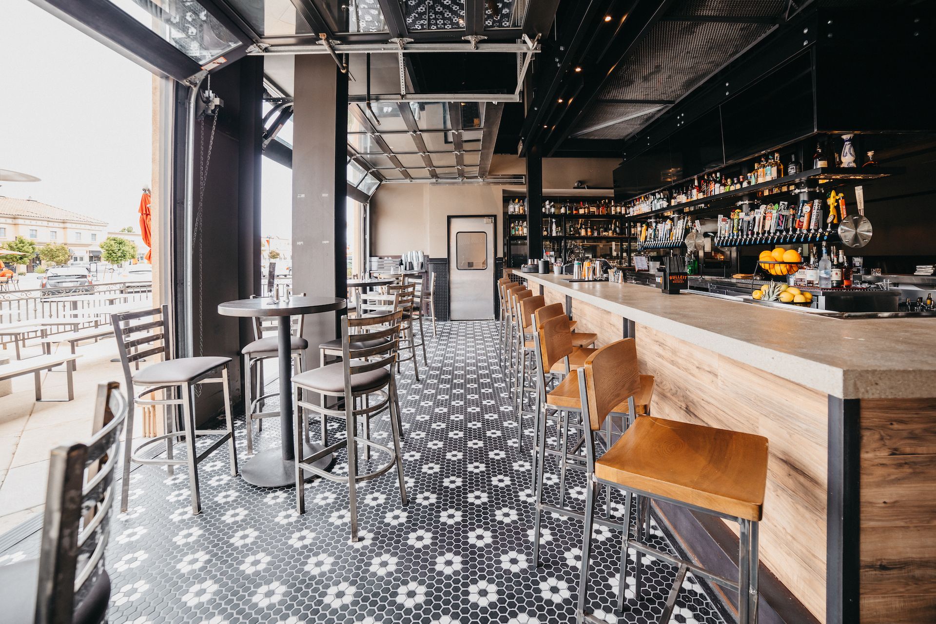 A restaurant with a long bar and tables and chairs.