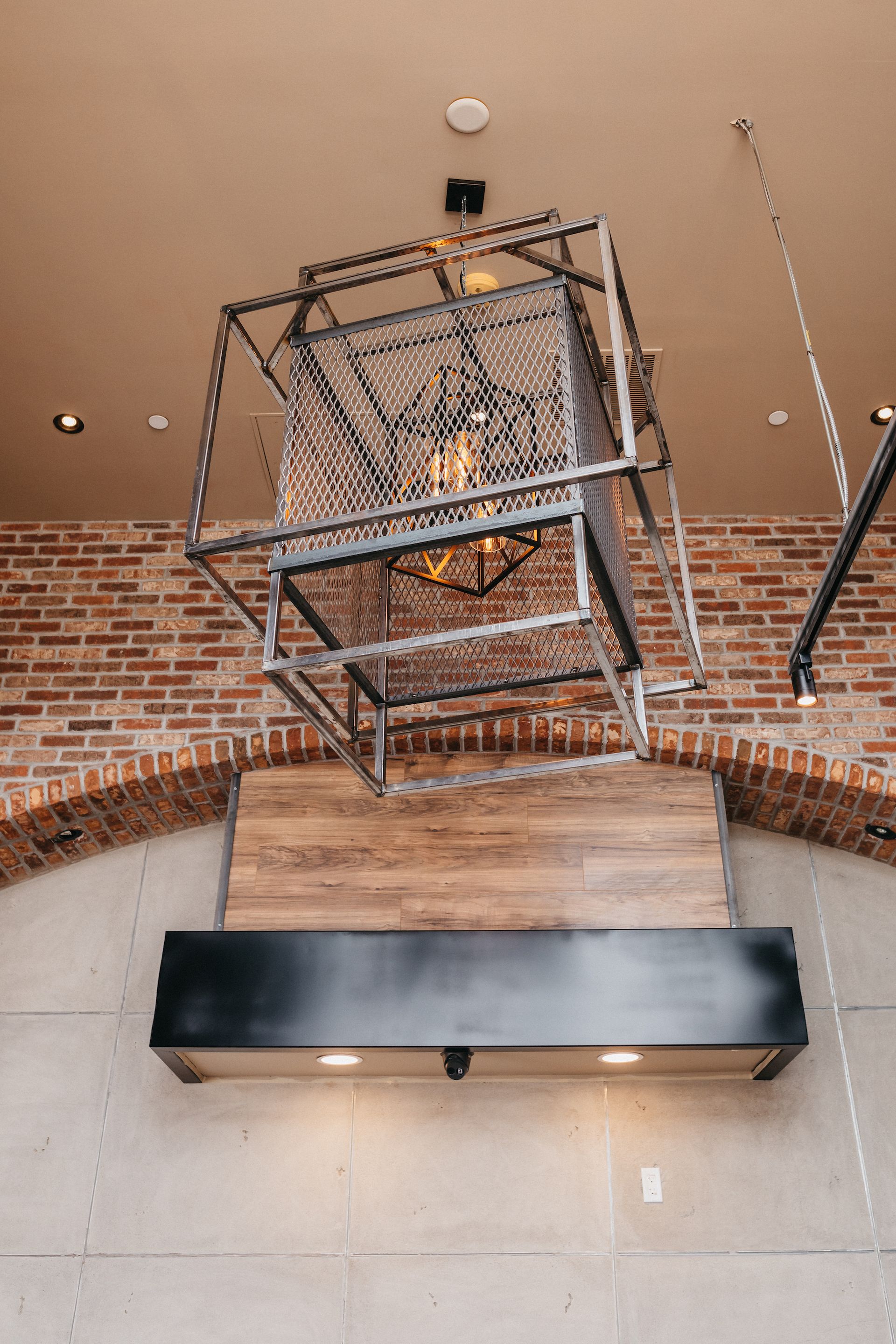 A chandelier is hanging from the ceiling in a room with a brick wall.