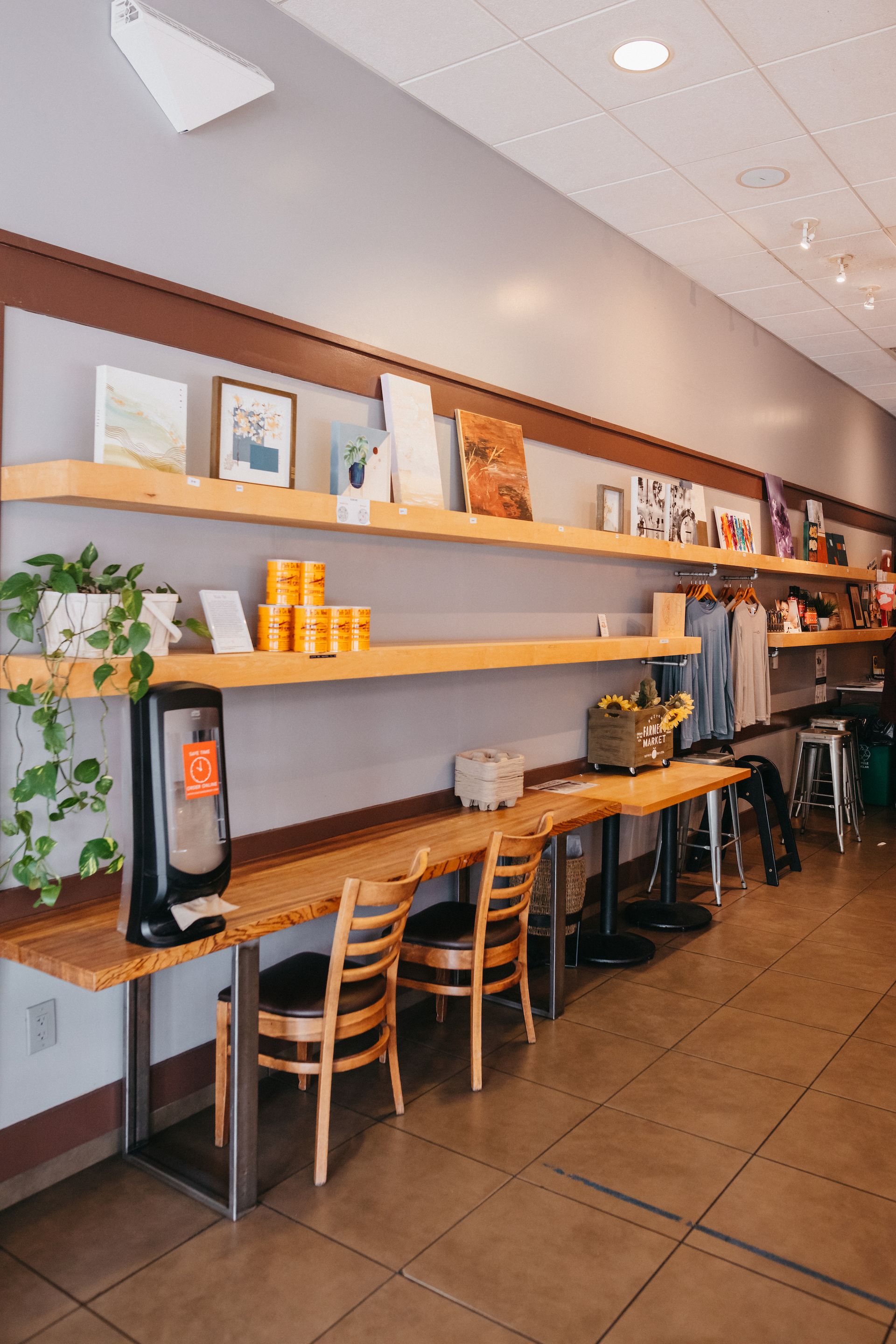 A restaurant with tables and chairs and shelves on the wall.