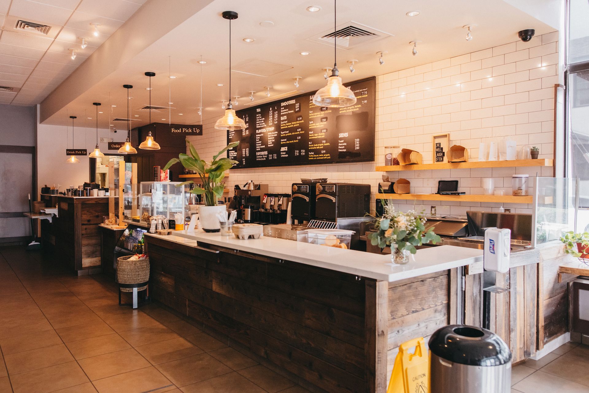 A coffee shop with a long counter and a chalkboard on the wall.