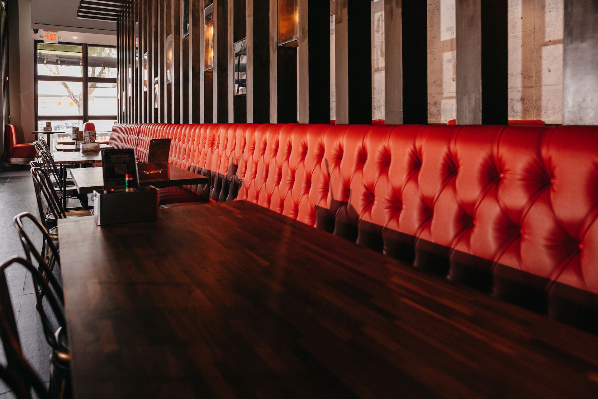 A restaurant with a long table and red benches.